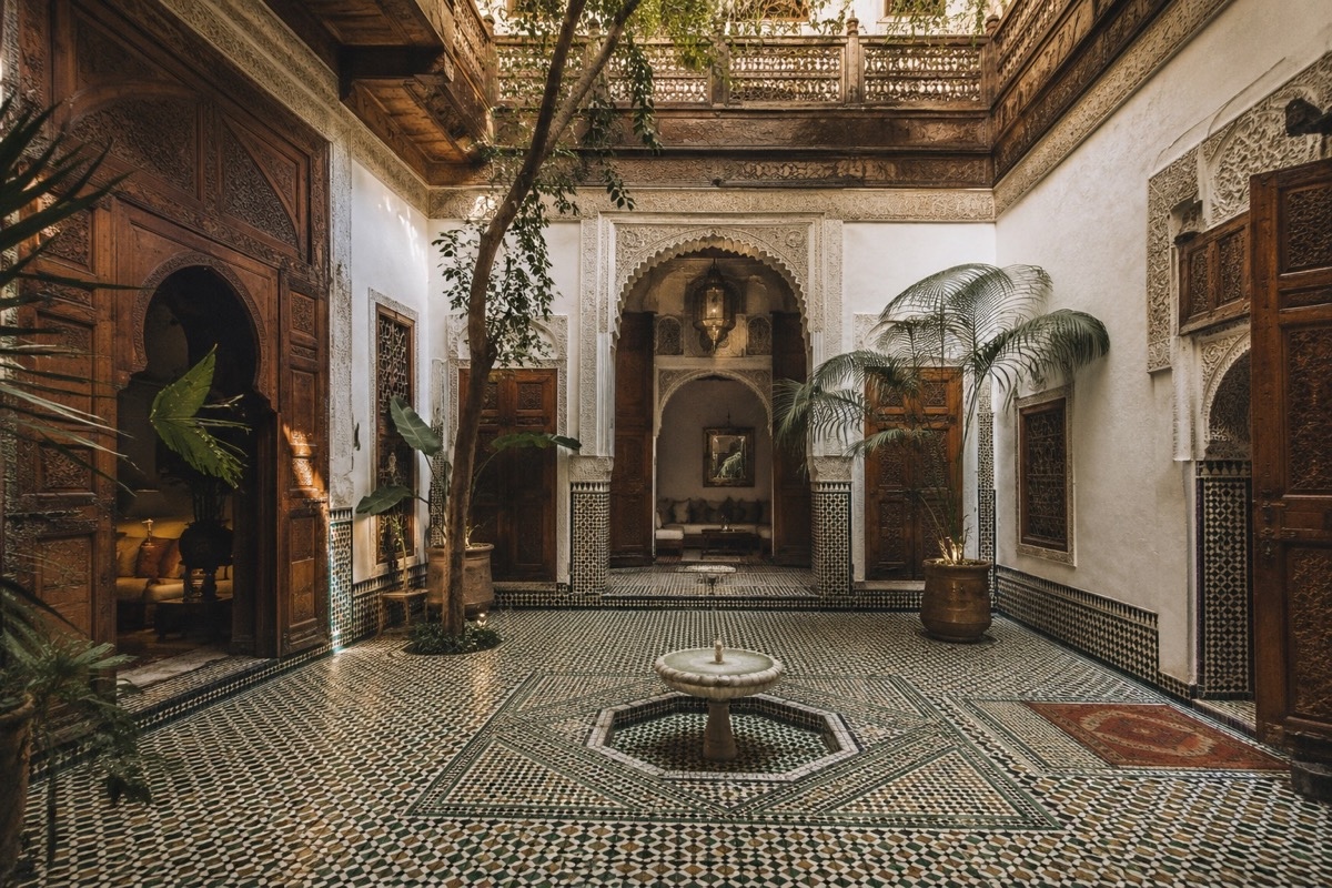 Offener Reiseführer auf traditionellem marokkanischem Tisch mit handgezeichneter Karte der Medina, Minztee-Glas und Notizbuch zur Reiseplanung